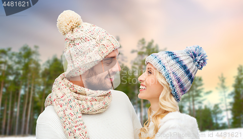 Image of happy couple in hats over winter forest background