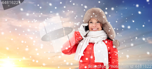 Image of happy woman in winter hat calling on smartphone