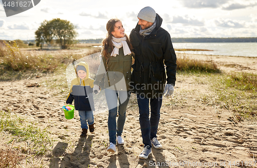 Image of happy family walking along autumn beach