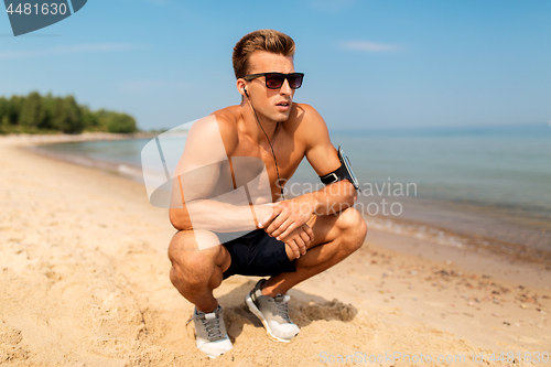 Image of male runner with earphones and arm band on beach