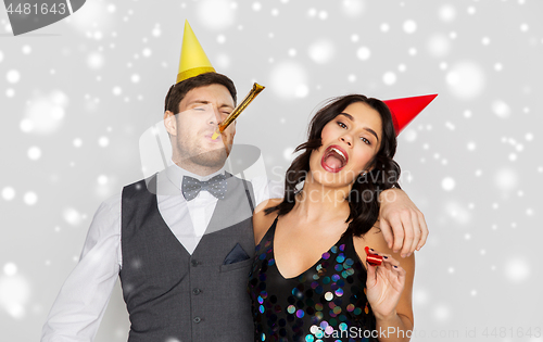 Image of happy couple with party blowers having fun