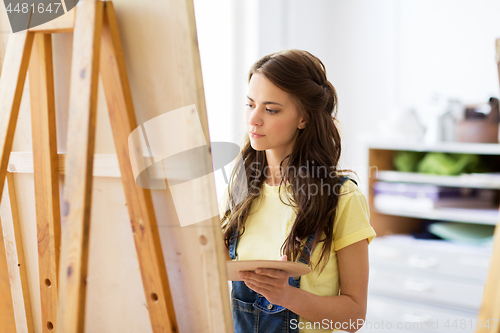 Image of student girl with easel painting at art school