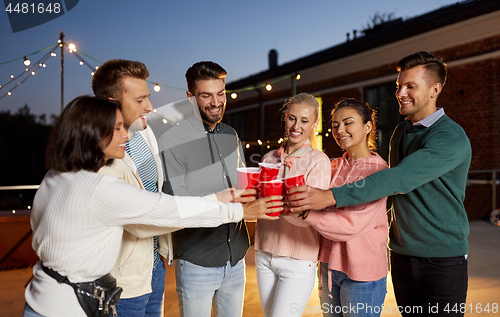 Image of friends clinking party cups on rooftop at night