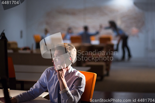 Image of man using mobile phone in dark office