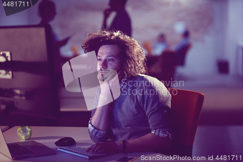 Image of man working on computer in dark office