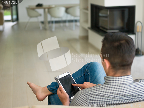 Image of man on sofa using tablet computer