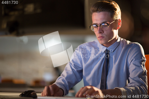 Image of man working on computer in dark office