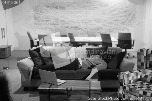 Image of man sleeping on a sofa  in a creative office