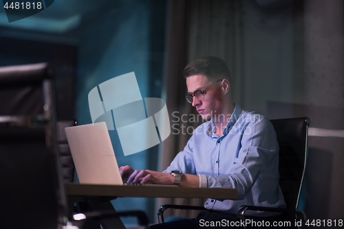 Image of man working on laptop in dark office