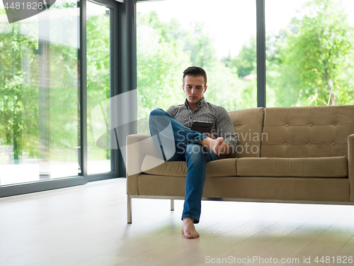 Image of man on sofa using tablet computer