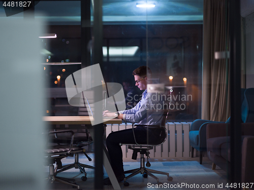 Image of man working on laptop in dark office