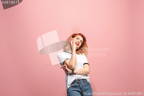 Image of The happy business woman is smiling and talking on the smartphone against pink background.