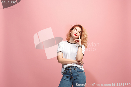 Image of Let me think. Doubtful pensive woman with thoughtful expression making choice against pink background