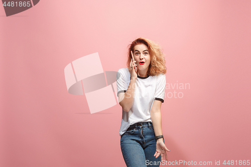 Image of The happy business woman is smiling and talking on the smartphone against pink background.