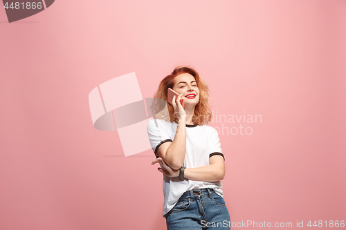 Image of The happy business woman is smiling and talking on the smartphone against pink background.