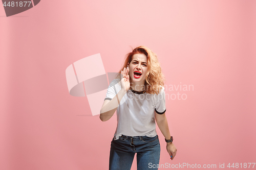 Image of The young emotional angry woman screaming on pink studio background