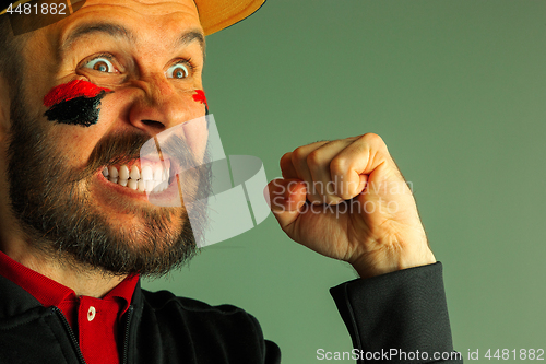 Image of Portrait of a man with the flag of the Germany painted on him face.