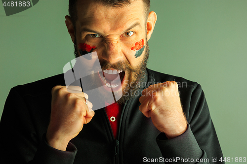 Image of Portrait of a man with the flag of the Germany painted on him face.