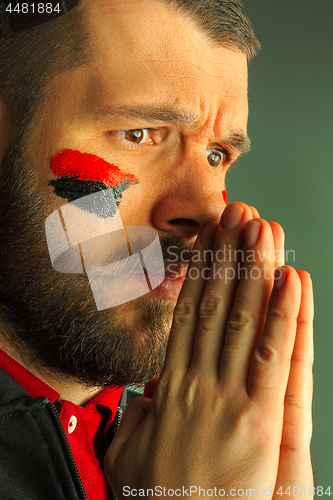 Image of Portrait of a man with the flag of the Germany painted on him face.