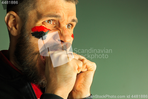 Image of Portrait of a man with the flag of the Germany painted on him face.