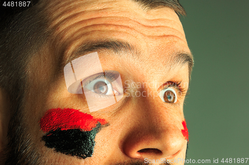 Image of Portrait of a man with the flag of the Germany painted on him face.