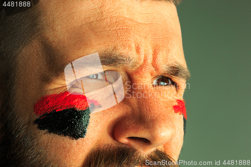 Image of Portrait of a man with the flag of the Germany painted on him face.