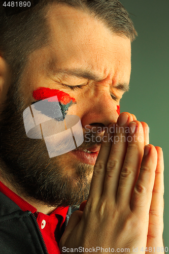 Image of Portrait of a man with the flag of the Germany painted on him face.