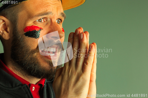 Image of Portrait of a man with the flag of the Germany painted on him face.