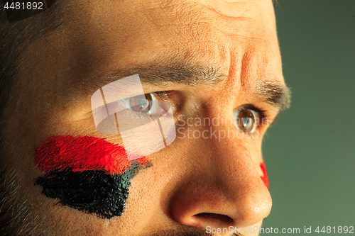 Image of Portrait of a man with the flag of the Germany painted on him face.