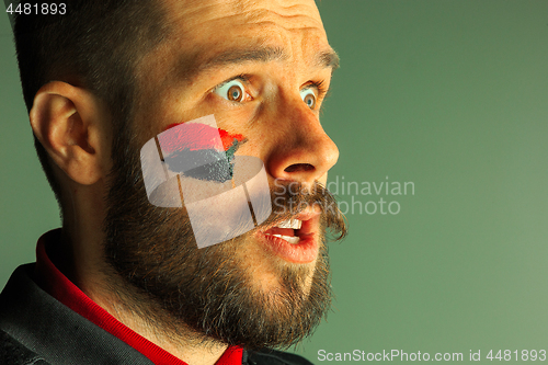 Image of Portrait of a man with the flag of the Germany painted on him face.