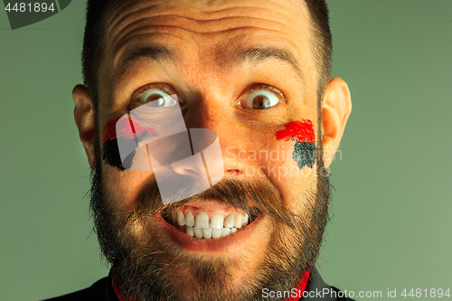 Image of Portrait of a man with the flag of the Germany painted on him face.