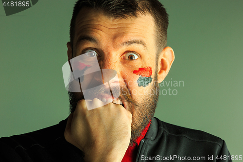 Image of Portrait of a man with the flag of the Germany painted on him face.