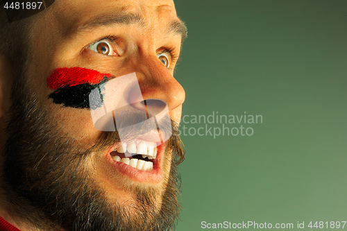 Image of Portrait of a man with the flag of the Germany painted on him face.