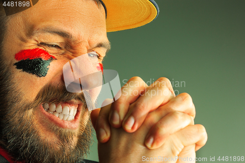 Image of Portrait of a man with the flag of the Germany painted on him face.