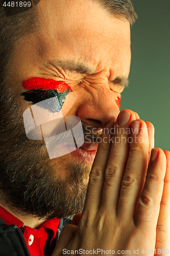 Image of Portrait of a man with the flag of the Germany painted on him face.