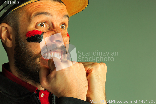 Image of Portrait of a man with the flag of the Germany painted on him face.