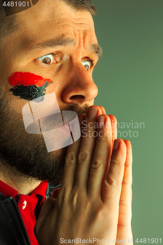 Image of Portrait of a man with the flag of the Germany painted on him face.