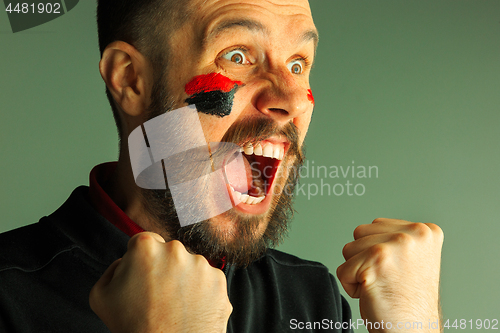 Image of Portrait of a man with the flag of the Germany painted on him face.