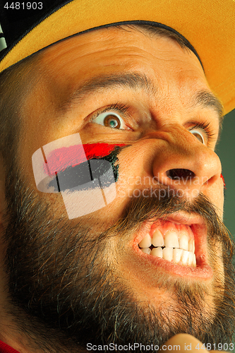 Image of Portrait of a man with the flag of the Germany painted on him face.