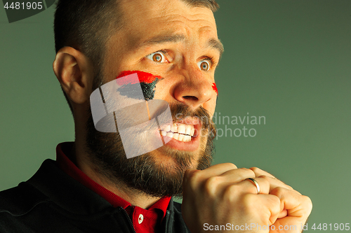 Image of Portrait of a man with the flag of the Germany painted on him face.