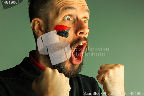 Image of Portrait of a man with the flag of the Germany painted on him face.