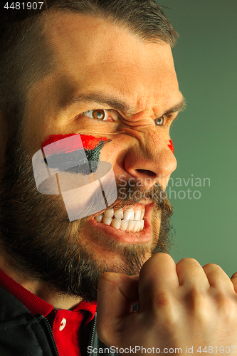 Image of Portrait of a man with the flag of the Germany painted on him face.