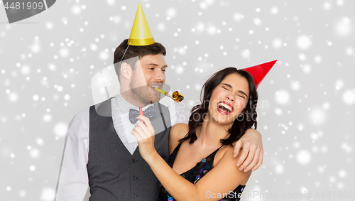 Image of happy couple with party blowers having fun