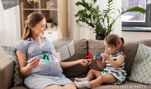 Image of pregnant mother and daughter with crane origami