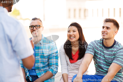 Image of happy international friends talking in city
