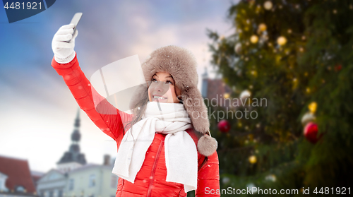 Image of woman taking selfie over christmas tree