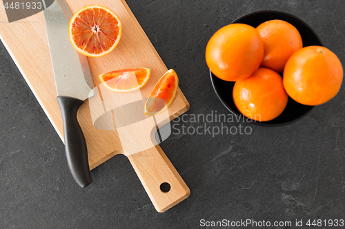 Image of close up of oranges and knife on cutting board