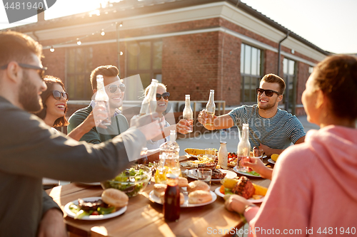 Image of happy friends toasting drinks at rooftop party