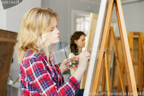 Image of girl with easel painting at art school studio