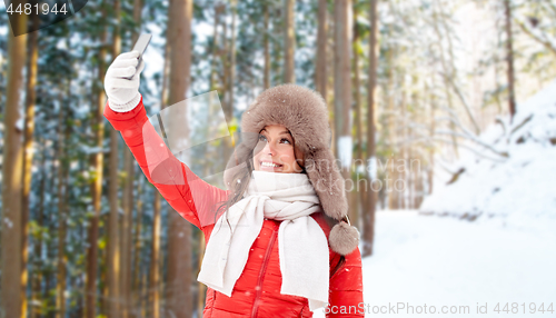 Image of happy woman taking selfie over winter forest